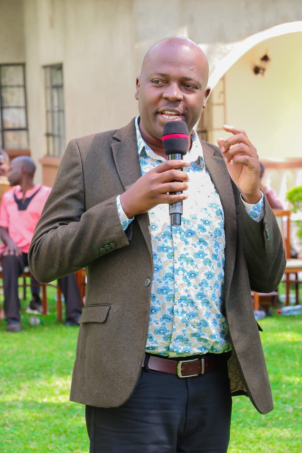 Eric Obwaka speaking with a microphone at an outdoor networking event